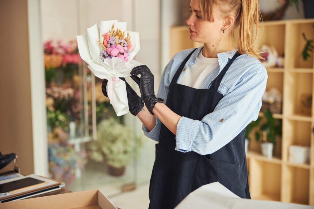 Focused experienced florist examining a floral arrangement in her hands